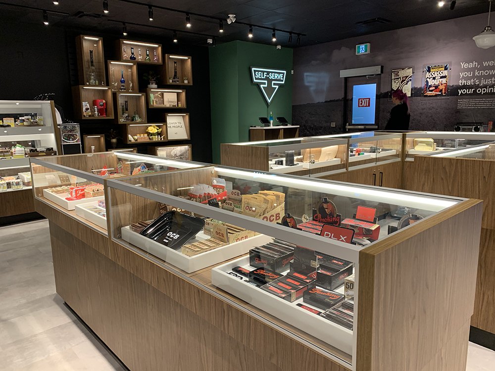 Inside the Friendly Stranger store: a glass display counter of cannabis products, wooden shelving and a neon 'Self-Serve' sign