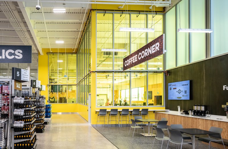 The Coffee Corner at Princess Auto: a yellow-glazed room with tables and a coffee bar beside The Shop