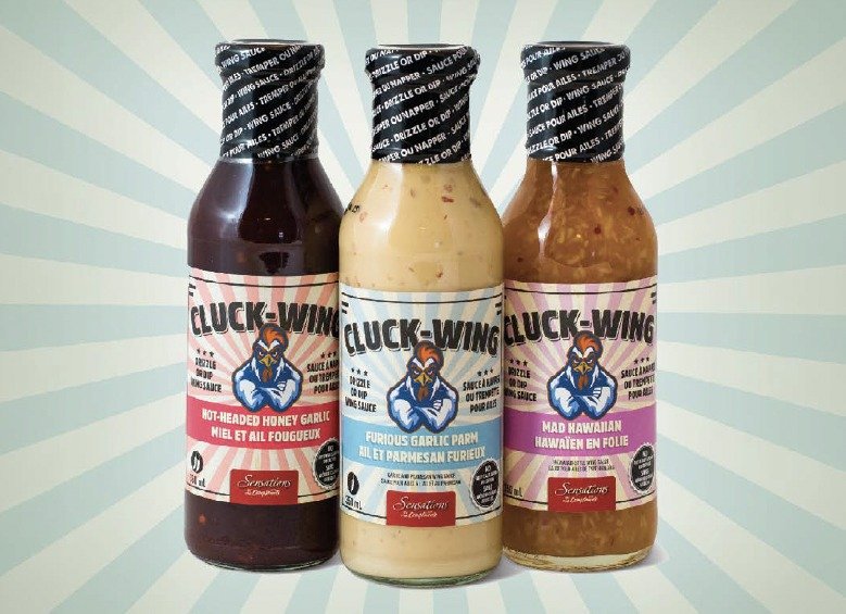Three Cluck-Wing sauce bottles with bilingual English and French labels: hot-headed honey garlic, furious garlic parm and mad Hawaiian
