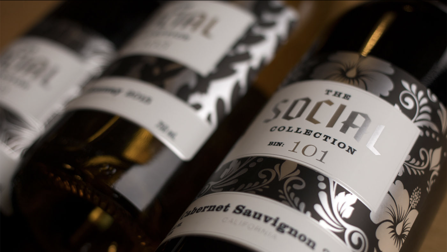 Close-up of The Social Collection Bin 101 Cabernet Sauvignon label, white and silver with a hibiscus pattern on black