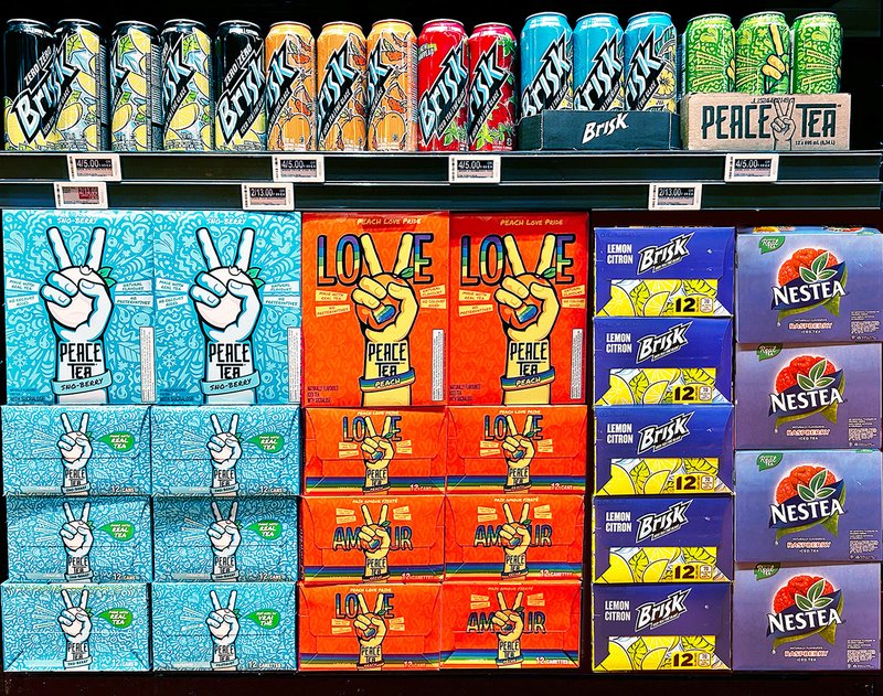 A store display of Peace Tea Peach Love Pride cases between Brisk and Nestea stacks