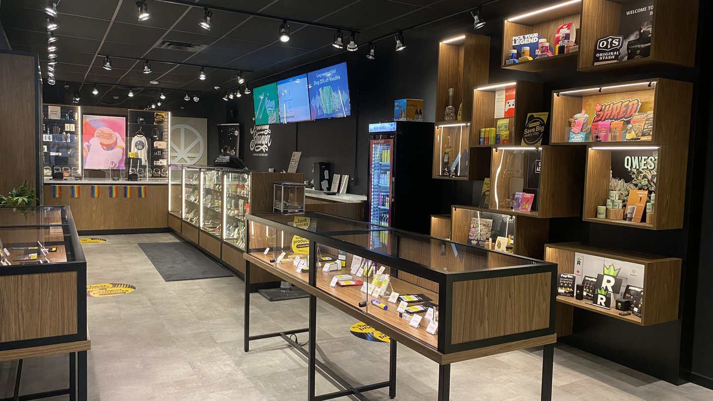 The Friendly Stranger store interior with glass display counters, wooden product shelves and a wall of screens