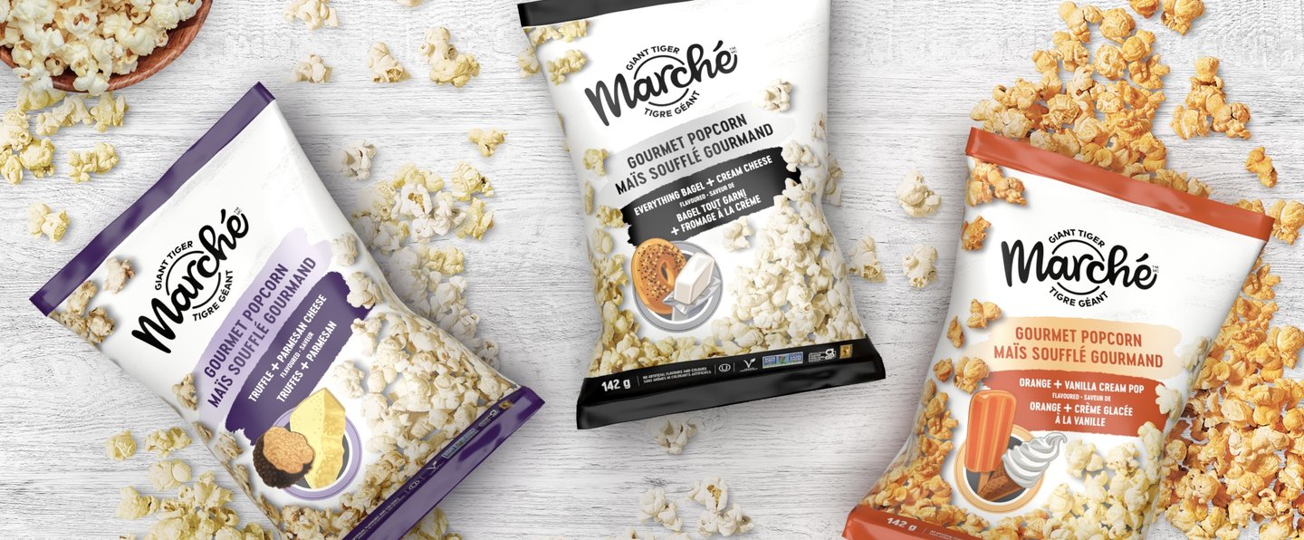 Three Marche gourmet popcorn bags on white boards with scattered popcorn