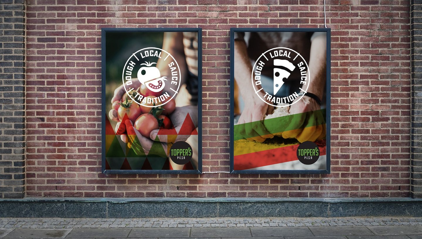 Two framed Topper's posters on a brick wall, each with the Dough Local Sauce Tradition stamp over hands holding pizza ingredients