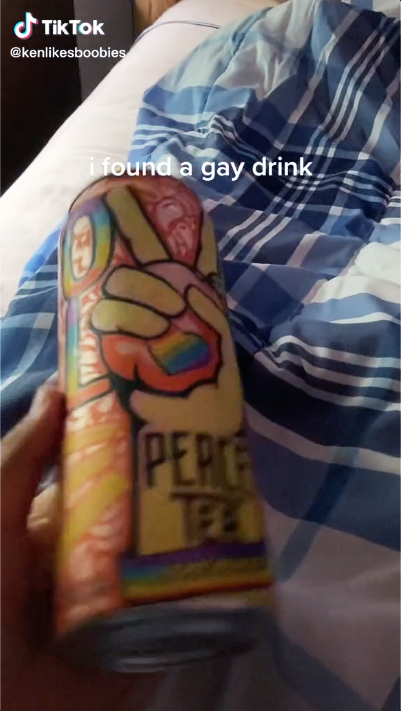 A TikTok screenshot of a Peace Tea Pride can held on a bed, captioned 'I found a gay drink'