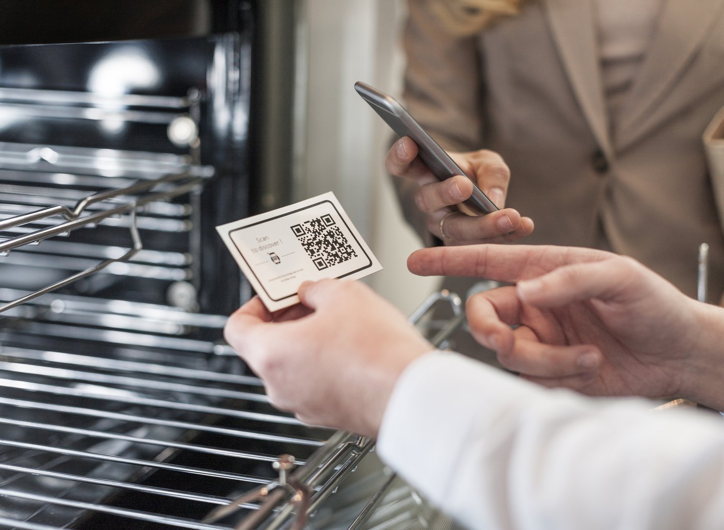 A shop assistant and customer scan a QR code card at an oven