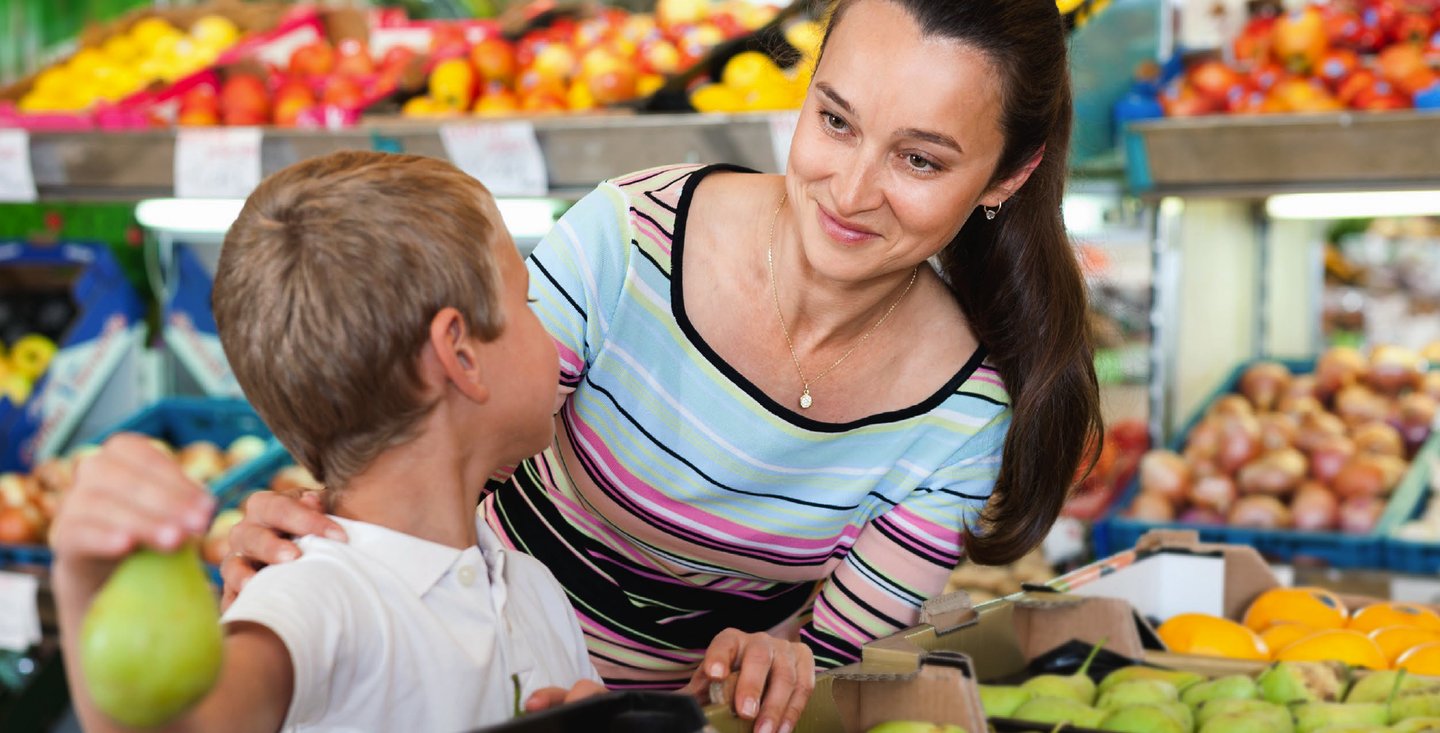 A mother and son shopping for fruit in a grocery produce section