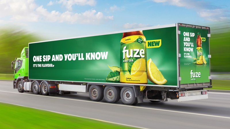 A transport truck wrapped in green Fuze iced tea advertising reading 'One sip and you'll know, it's the flavour'