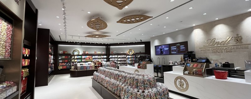 Inside the redesigned Lindt store: a Pick & Mix island of Lindor truffles and the cash desk under the Lindt logo wall