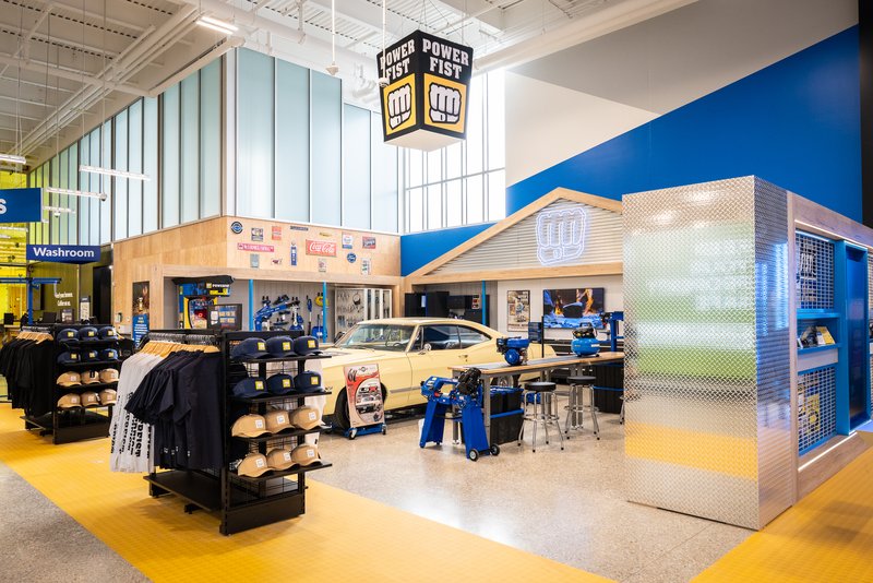 The finished Powerfist zone: an aspirational garage with a yellow vintage car, apparel displays and a Powerfist sign overhead