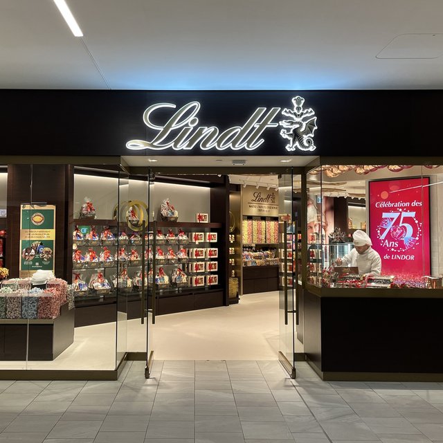 The Lindt flagship storefront at the Montreal Eaton Centre, with the illuminated Lindt sign over glass doors and shelves of chocolate inside